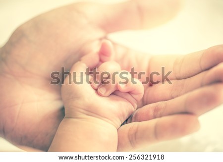 father holding baby hand in vintage filtered style