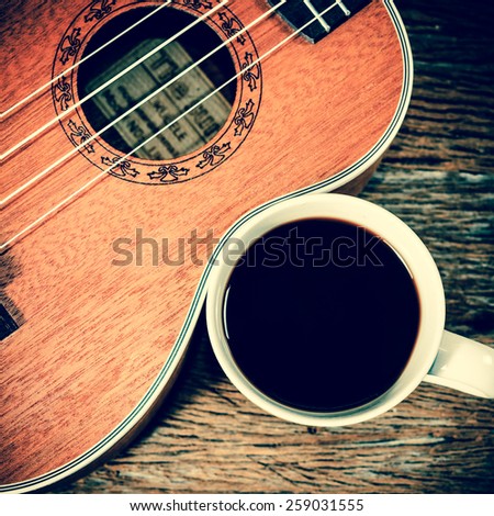 coffee cup and Ukulele on wooden table ;vintage filtered style