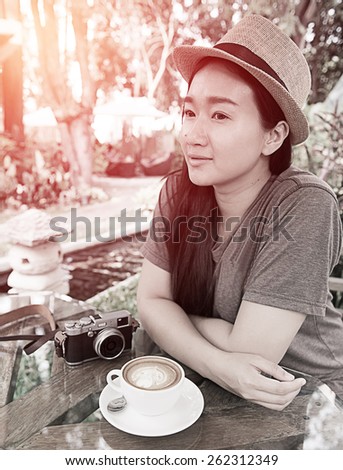 beautiful woman with classic camera and coffee latte art in garden ; vintage filtered tone style