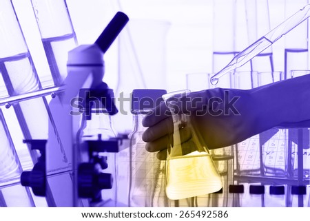Flask in scientist hand with lab equipment background