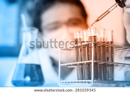 Glass laboratory chemical test tubes with liquid.Man wears protective goggles