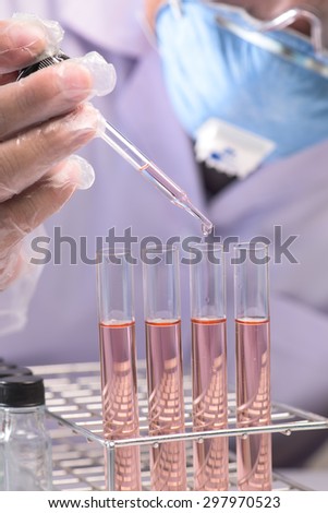 scientist  dropping chemical liquid to flask with lab glassware background, Laboratory research concept