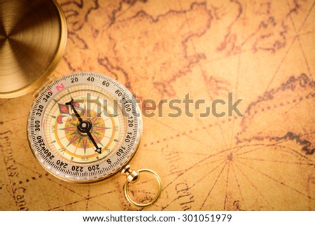 Old  gold vintage compass on vintage map:Heading south