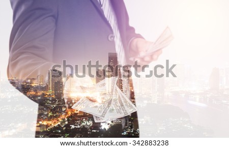 Double exposure of Businessman with money in hand  with cityscape blurred building background, US dollar (USD) bills - investment, success and profitable business concepts