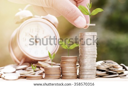 Close up of male hand stacking gold coins with green bokeh background ,Business Finance and Money concept,Save money for prepare in the future.Trees growing on coin