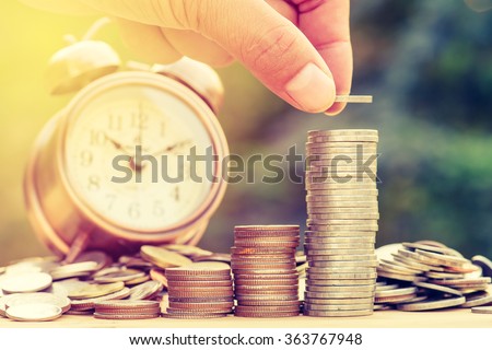 Close up of male hand stacking gold coins with green bokeh background ,Business Finance and Money concept,Save money for prepare in the future.