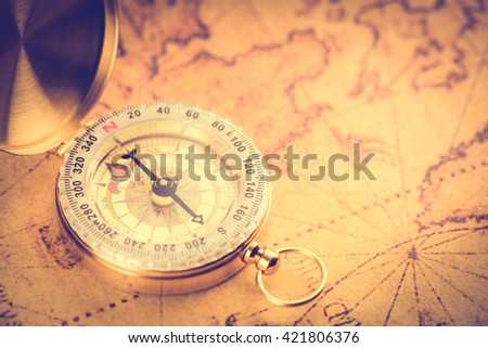 Old  gold vintage compass on vintage map:Heading south
