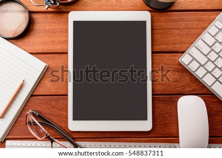 mockup tablet similar to ipad style on wood desk. empty display.keyboard and office stuff, workplace, top view