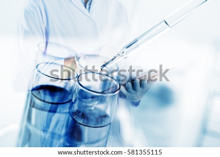 scientist use tablet with science laboratory test tubes. science background