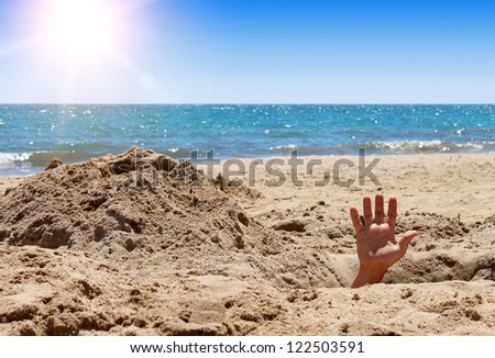 Human hand out of the hole on the sandy beach