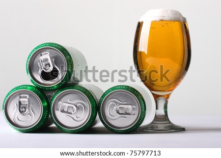 Green cans of beer with a full glass of foamy beer. Isolated on white background.