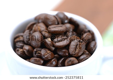Coffee cup filled with coffee beans. Very shallow focus on coffee beans in cup.
