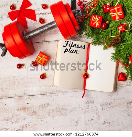 Christmas or New Year on a white wooden background. Diary with the inscription 2019 fitness plan. Composition with dumbbells, gift, red glass balls, fir tree branches for healthy lifestyle and sport