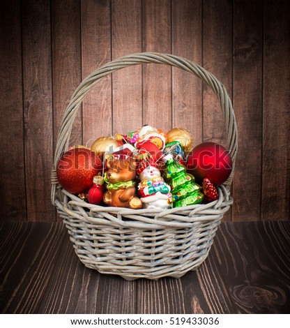 Christmas or New Year background: basket with colored glass toys and balls, decoration and gifts on wooden background