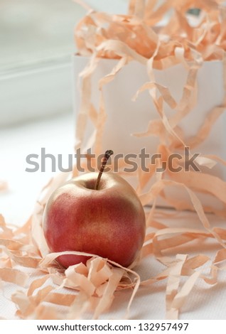 An apple painted in gold near a white gift box