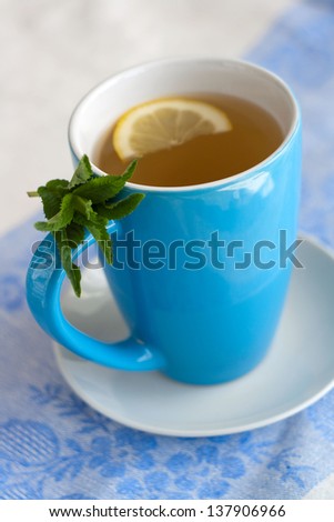 Hot or cold green tea with lemon and mint on the white and blue napkin