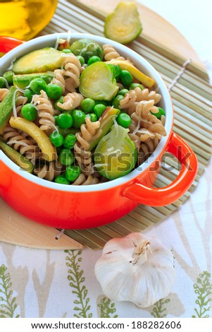 Wholegrain pasta with green vegetables in the orange ceramic pan