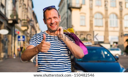 Male shopper holding shopping bags looking very happy
