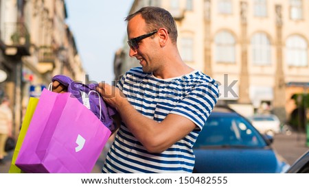 Male shopper holding shopping bags looking very happy