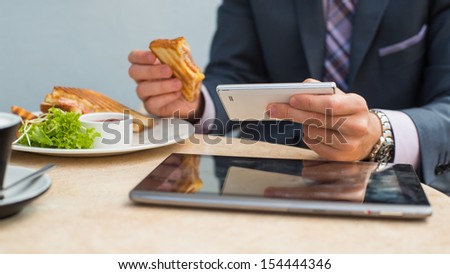 Businessman with tablet and smartphone during breakfast Businessman with tablet and smartphone during breakfast