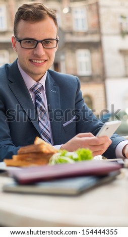Businessman with mobile phone during breakfast.