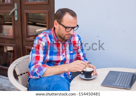 Young man sitting in cafe with laptop and coffee.
