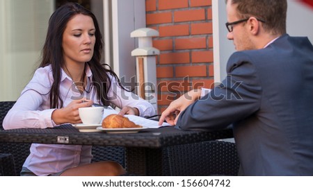 Businessman and businesswomen having a meeting in cafe. He is signing a contract.