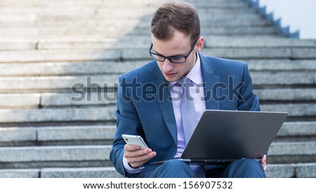 Young happy man working with mobile phone and tablet, horizontal portrait.