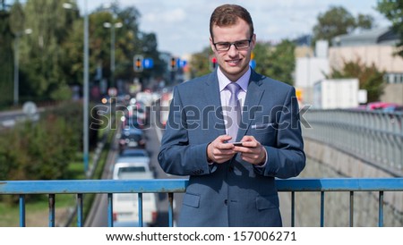 Businessman with mobile phone. In the background bustling street.