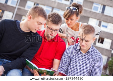 Young students reading books at the school playing field.