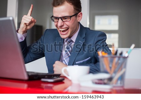 Young happy businessman with laptop computer in office. Expression of emotions.