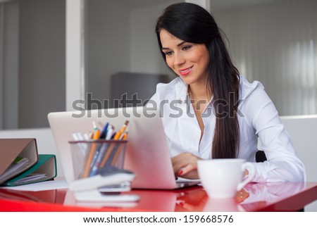 Beautiful cheerful secretary working in office with laptop computer.