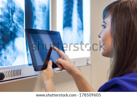 Female doctor using a tablet computer in a hospital. She is wearing blue smock
