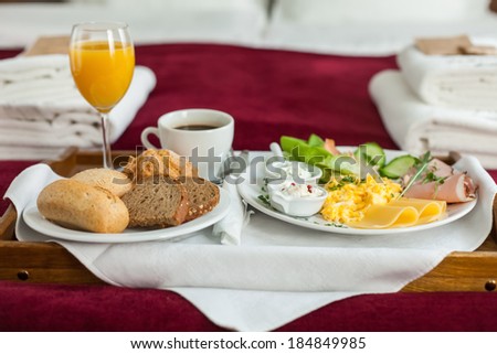 Photo of tray with english breakfast food on the bed inside a bedroom