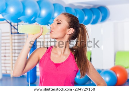 Young girl drinking isotonic drink, gym