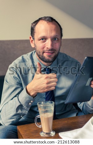 Businessman working on tablet pc during breakfast at home/hotel. Indoor photo