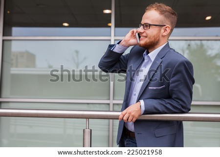 Caucasian businessman outside office using mobile phone on a office block background. Copy space