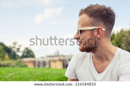 Portrait of bearded young man. Caucasian man smiling happy on sunny summer or spring day outside in park.
