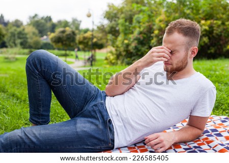 Portrait of bearded young man. Sad caucasian man on sunny summer or spring day outside in park