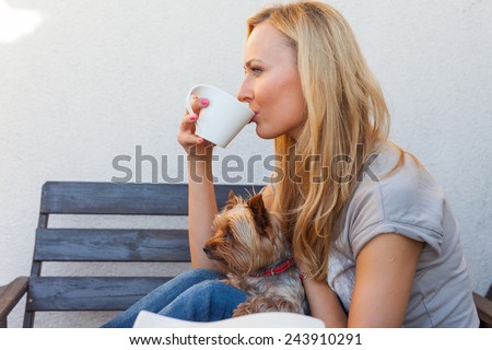 A pretty caucasian woman at home sitting on the porch and drinking coffee. She is resting. Outdoor photo.