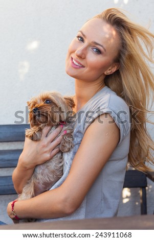 A pretty caucasian woman at home sitting on the porch and playing with a dog. Outdoor photo.