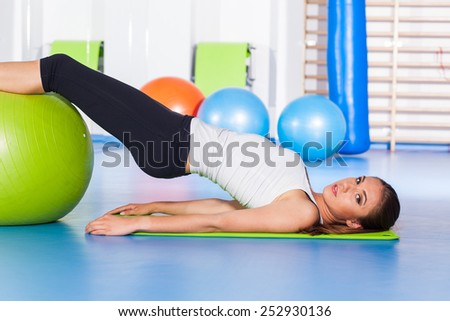 fitness, sport, training and lifestyle concept - woman stretching and doing physical exercises  with big green fitness ball in gym.