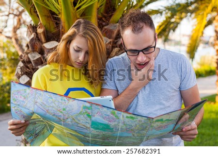 Happy tourist couple with map pointing at destination. Vacation time. Copy space.