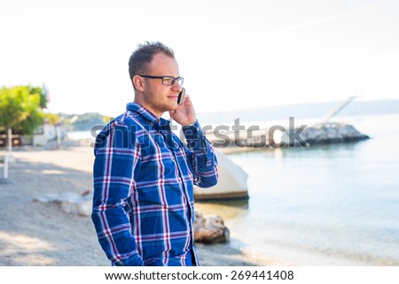 Young tourist in shirt with mobile phone on a Croatian beach. Positive emotion. Vacation time.