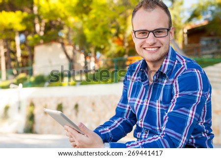 Young tourist in shirt with mobile tablet pc on a beach. Positive emotion. Vacation time.