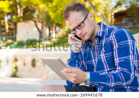 Young tourist in shirt with mobile phone and tablet pc on a Croatian beach. Negative emotion. Vacation time