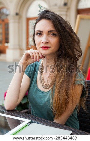 Brown hair girl sitting behind table in cafÃ?Â?Ã?Â© restaurant and smiling