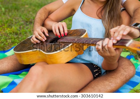 Young man teaches his girlfriend to play the guitar