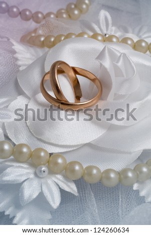 Two gold rings and pearl on wedding background.