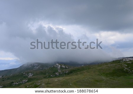Showers in low mountains: a shred of a gray cloud sails over the steppe. Rainy day in the highlands of Crimea